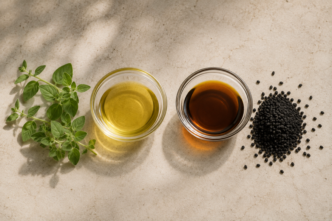 Oregano oil with fresh leaves beside black seed oil with Nigella sativa seeds