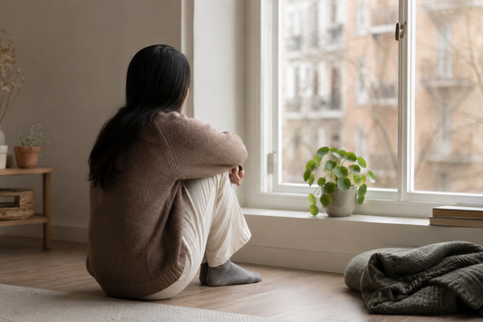 Person sitting quietly beside a window in soft afternoon light
