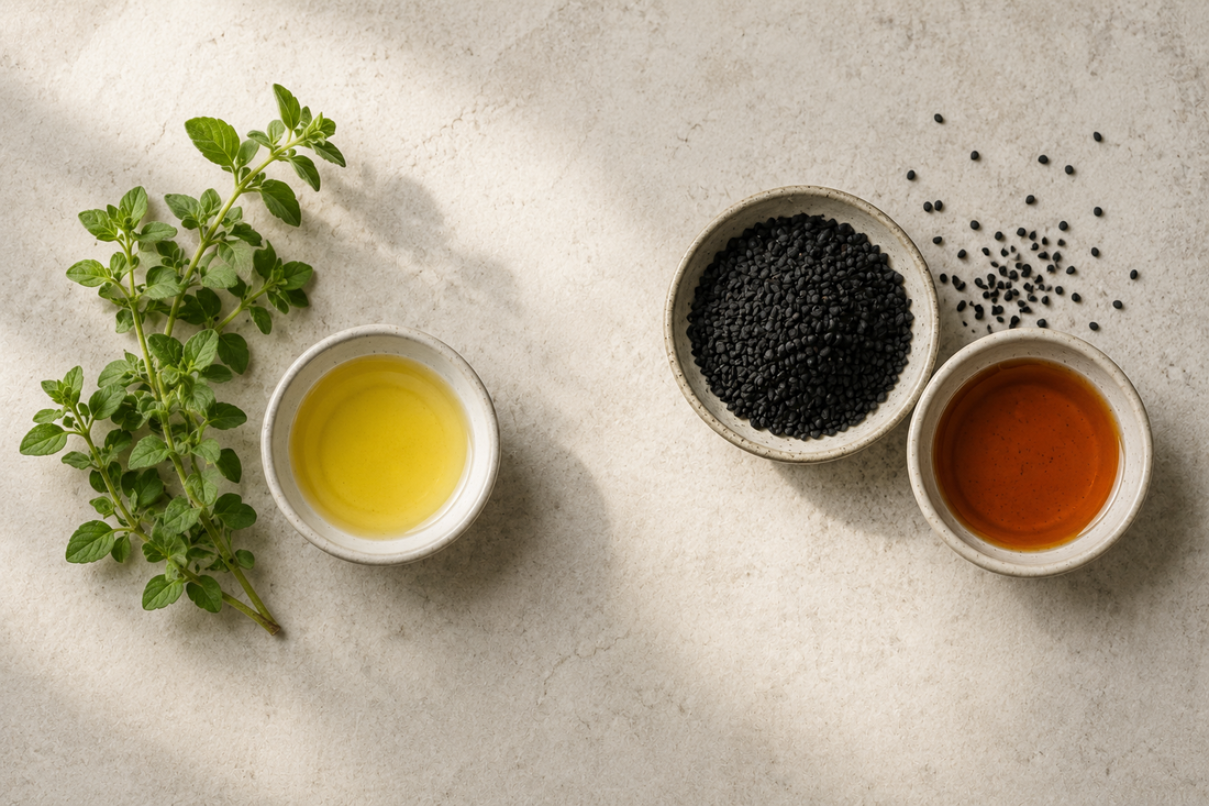 Fresh oregano with golden oil beside black Nigella sativa seeds with amber oil