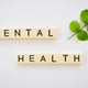 the word mental health spelled with scrabbles next to a green leaf