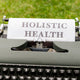 a close up of a typewriter with a paper that says holstic health