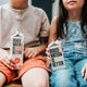 a boy and a girl sitting on a table holding boxes of booze