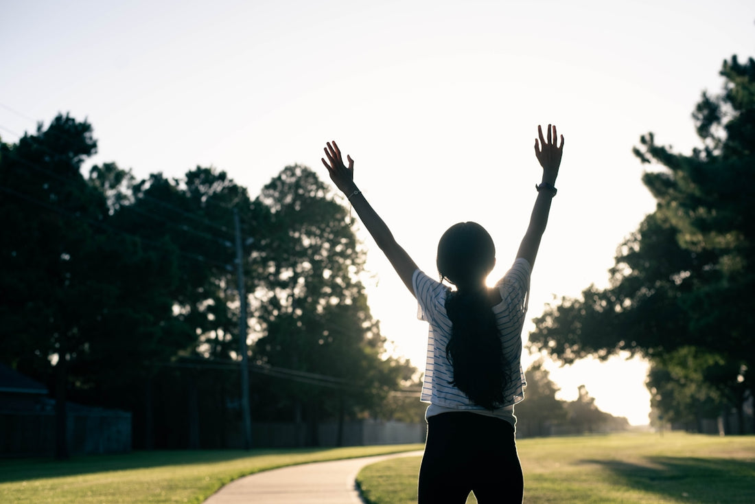A person standing on a road with their arms in the air