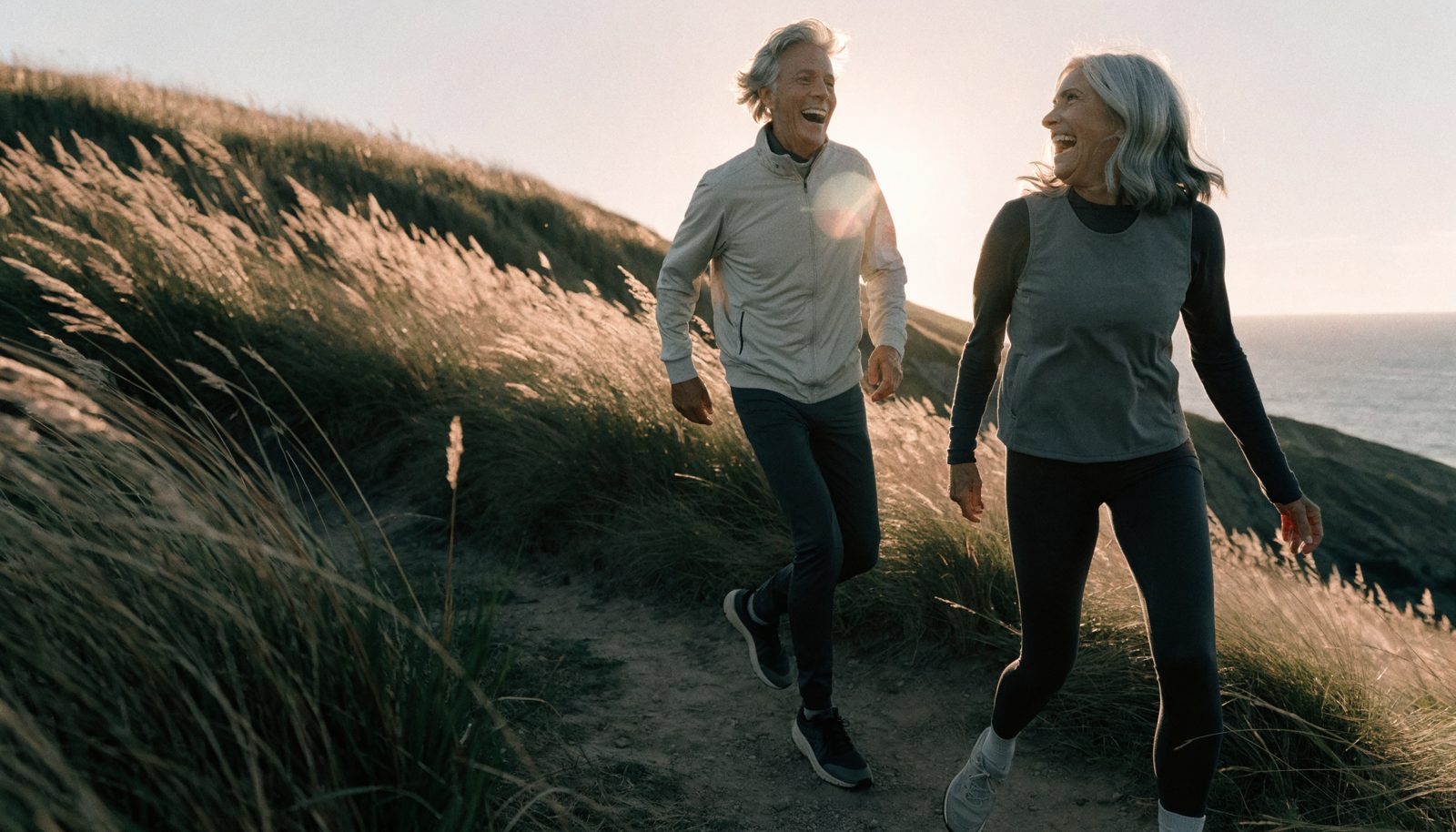 Active couple hiking a coastal trail at golden hour